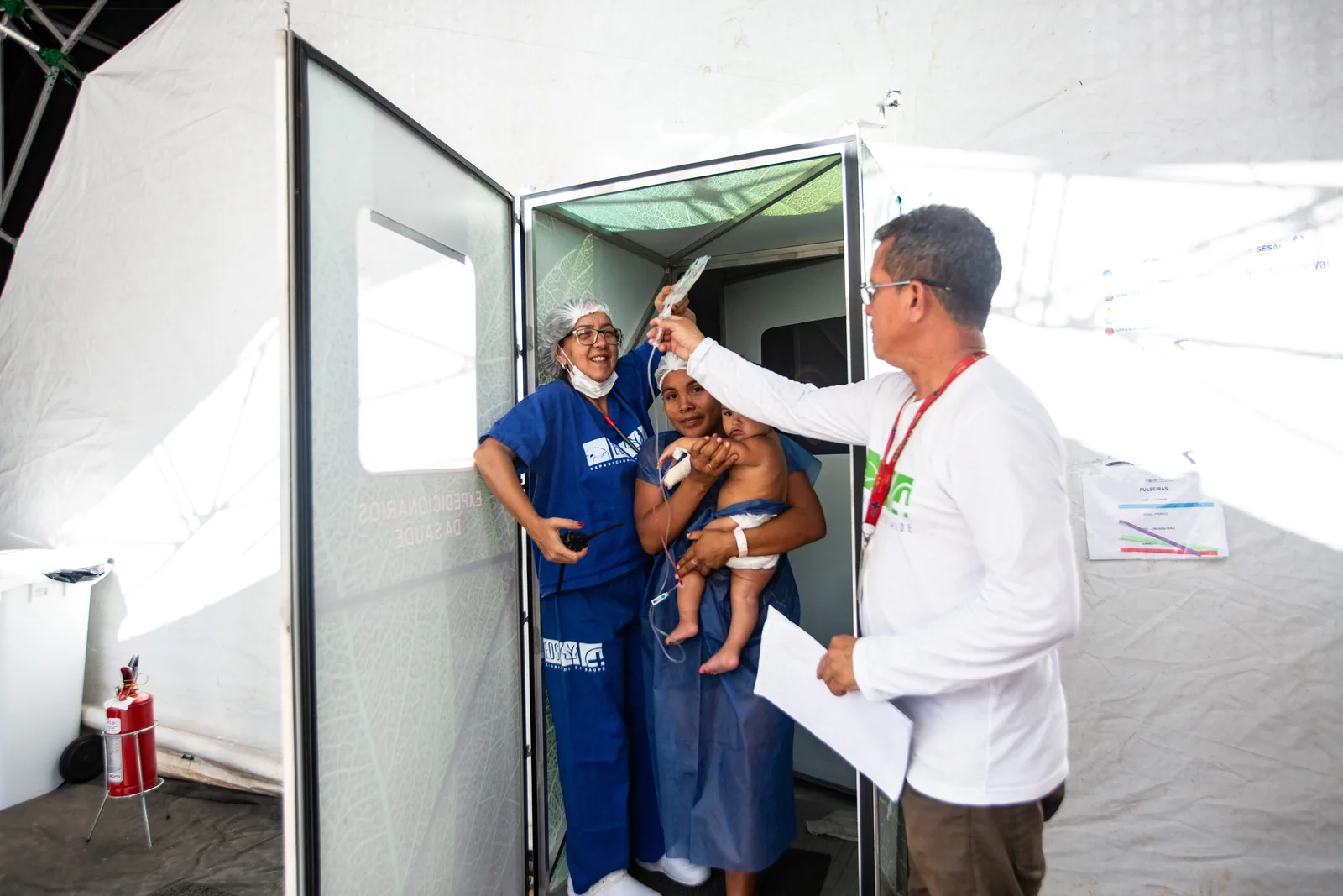 Médico examina uma criança no colo da mãe na porta do centro cirúrgico