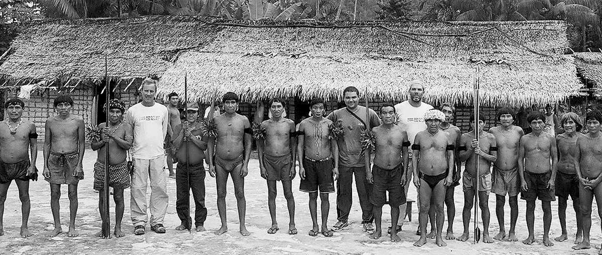Foto em preto e branco dos médicos ao lado de uma comunidade indígena, no início da EDS