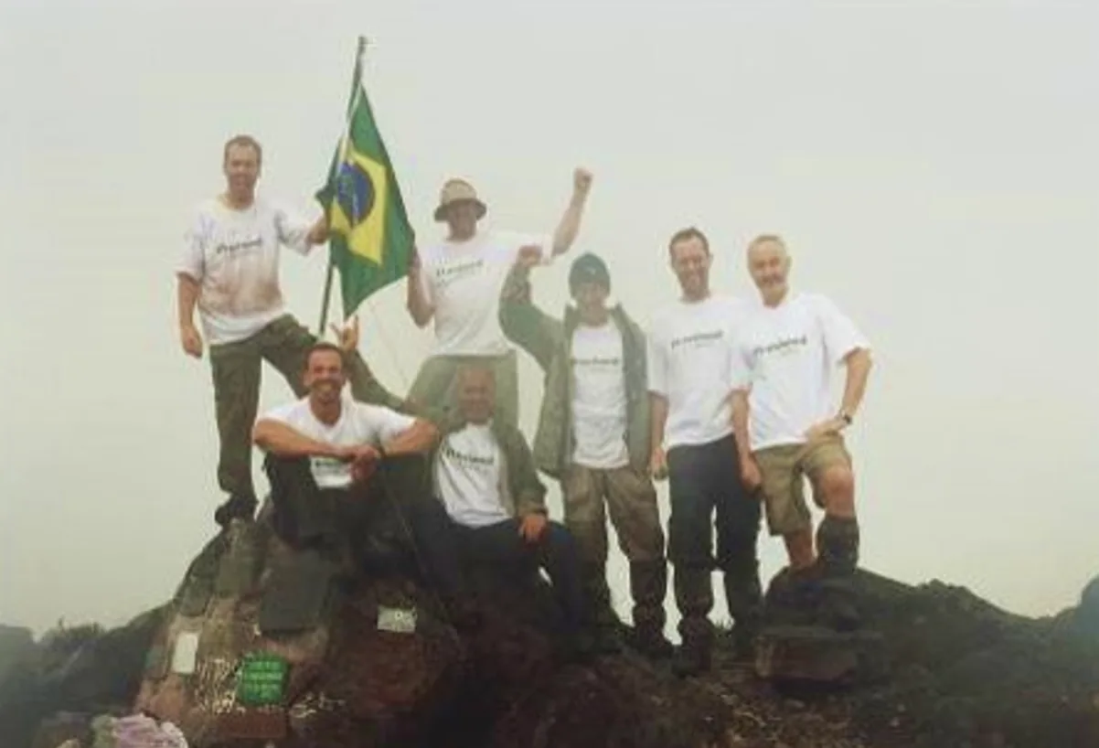 O grupo de amigos no alto do Pico da Neblina, com a bandeira do Brasil